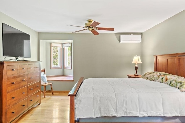 bedroom featuring light wood-type flooring, a wall mounted air conditioner, and a ceiling fan