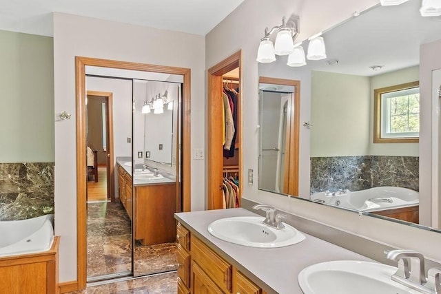 bathroom with double vanity, a garden tub, and a walk in closet