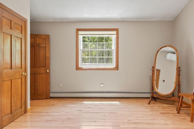 unfurnished bedroom featuring light wood-type flooring and a wall unit AC