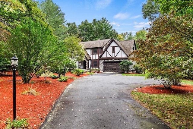tudor house featuring driveway, a garage, and stucco siding