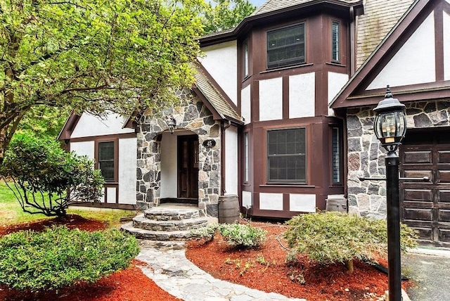 property entrance with stucco siding, stone siding, and an attached garage