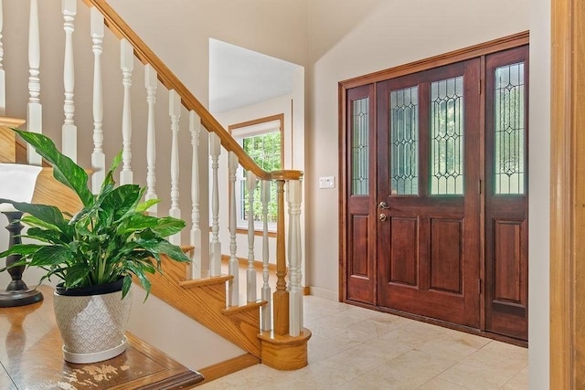 foyer entrance with stairs, baseboards, and light tile patterned flooring