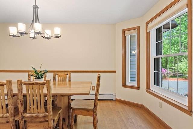 dining space featuring a chandelier, light wood-type flooring, healthy amount of natural light, and baseboard heating