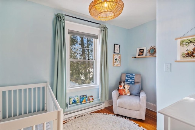 bedroom featuring wood finished floors, a baseboard radiator, and baseboards