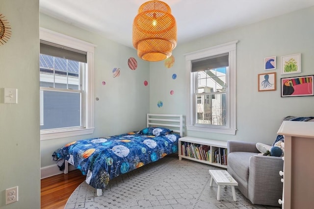 bedroom featuring multiple windows, wood finished floors, and baseboards