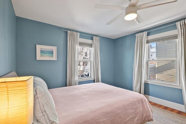 bedroom featuring wood finished floors, baseboards, and a ceiling fan