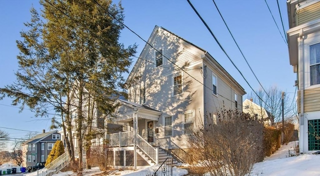 view of snow covered exterior with stairway and a porch