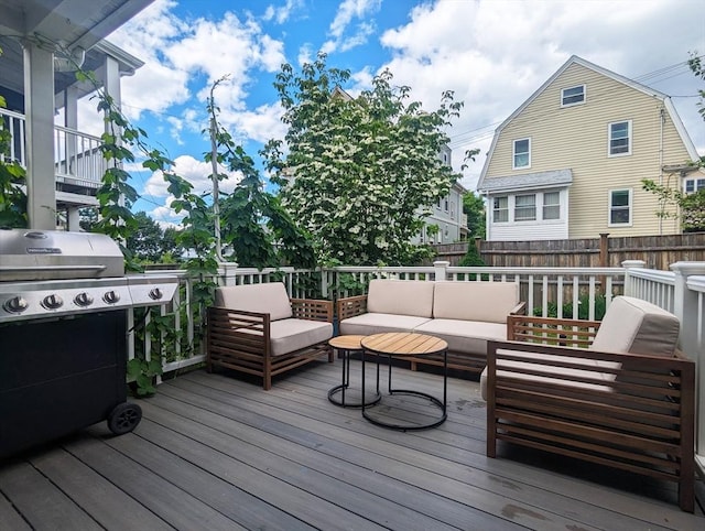 wooden deck featuring an outdoor living space, fence, and a grill