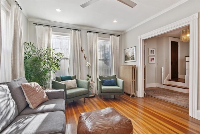 living area with crown molding, wood finished floors, a ceiling fan, and recessed lighting