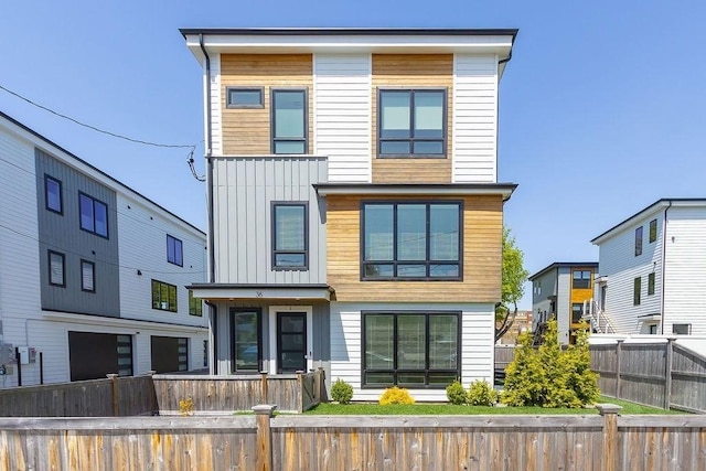 modern home featuring board and batten siding and a fenced front yard