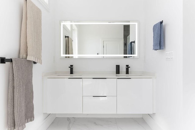 full bath featuring double vanity, a sink, and marble finish floor