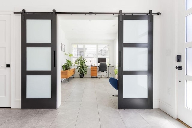 entryway with a barn door and light tile patterned flooring