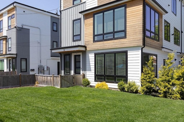 rear view of house with fence and a lawn