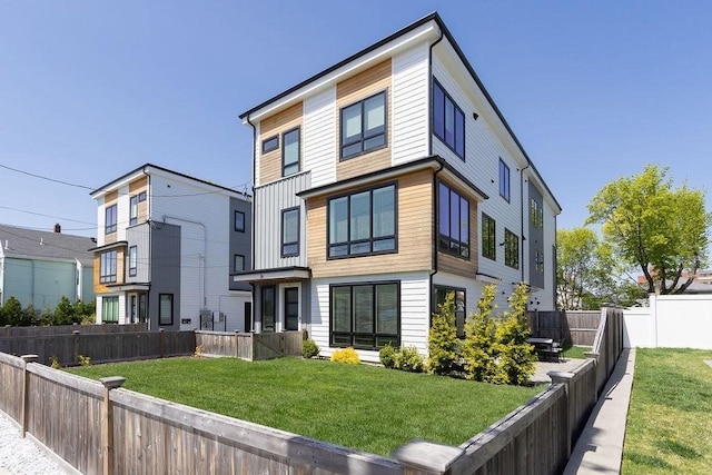 rear view of property with a fenced backyard and a yard