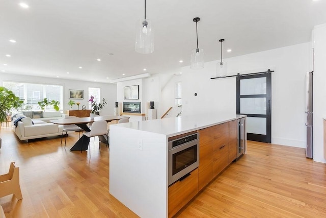 kitchen featuring a barn door, light wood-style floors, stainless steel appliances, a large island, and modern cabinets