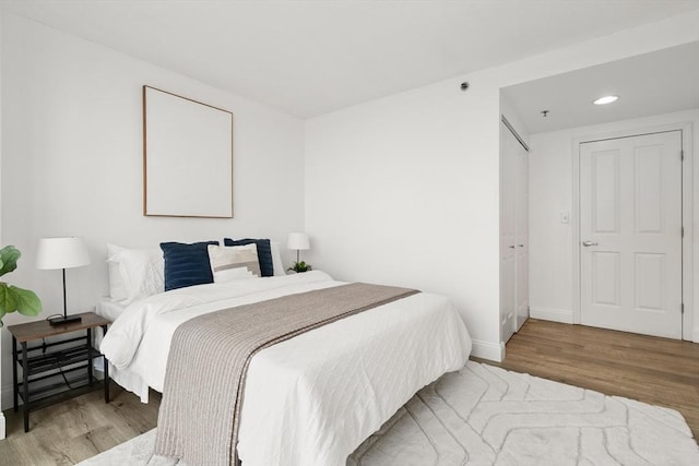 bedroom with wood finished floors, baseboards, and recessed lighting