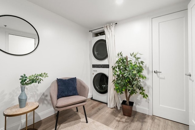 laundry room with stacked washing machine and dryer, wood finished floors, and baseboards