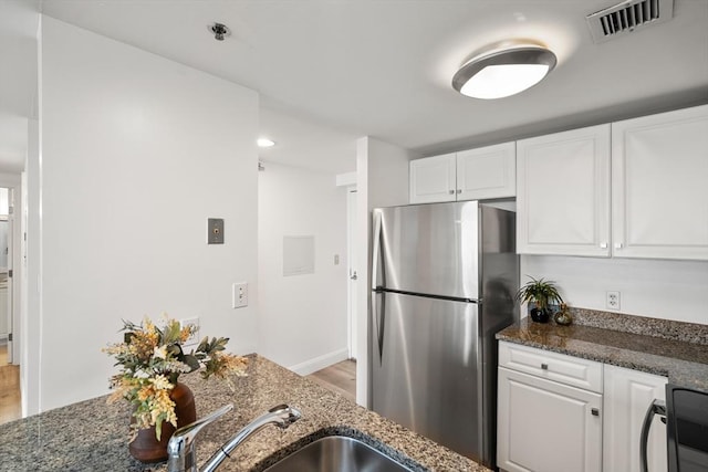 kitchen featuring freestanding refrigerator, light wood-style flooring, white cabinetry, dark stone countertops, and recessed lighting