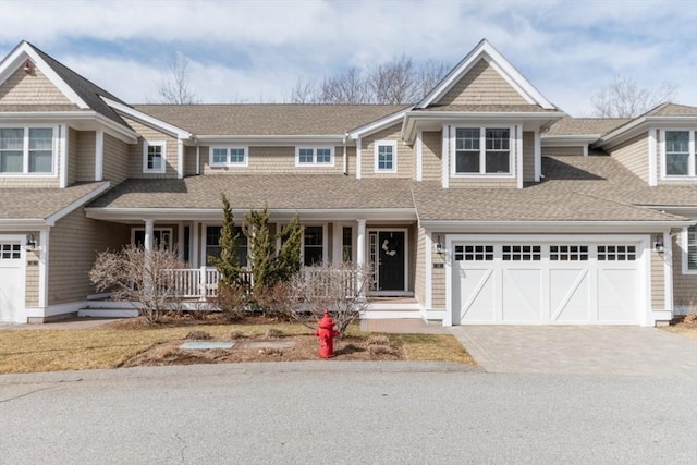 view of front facade featuring a garage, a porch, driveway, and a shingled roof