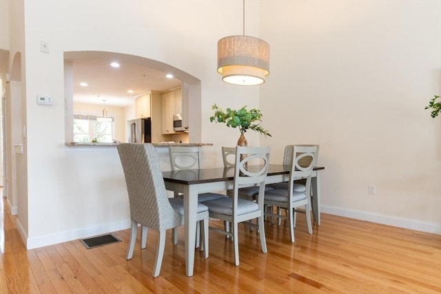 dining space featuring visible vents, baseboards, recessed lighting, arched walkways, and light wood-style floors