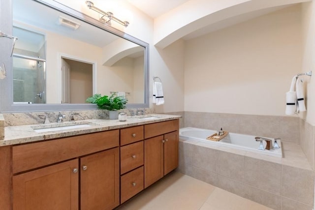 bathroom featuring a bath, a shower stall, double vanity, and a sink