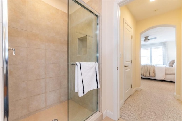 bathroom featuring connected bathroom, a stall shower, and baseboards