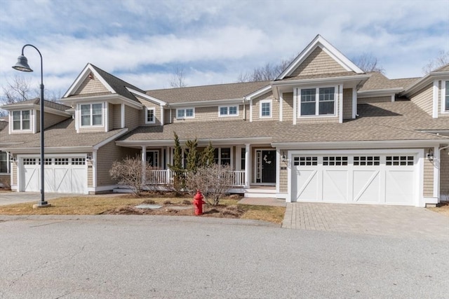 view of front of house featuring covered porch, driveway, and a shingled roof