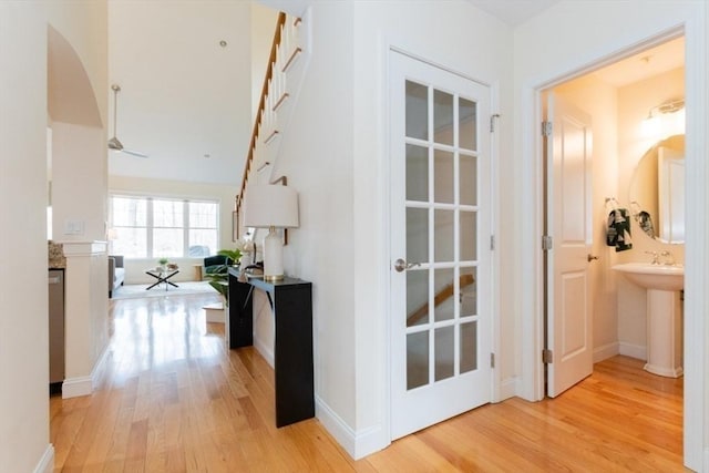 hall with light wood-style flooring, baseboards, and a sink