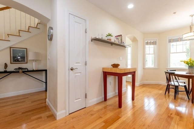 dining space featuring recessed lighting, arched walkways, light wood-style floors, baseboards, and stairs