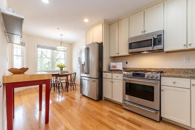 kitchen featuring light wood finished floors, light stone countertops, pendant lighting, recessed lighting, and stainless steel appliances