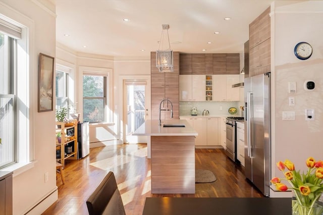 kitchen with dark wood-type flooring, light countertops, decorative backsplash, stainless steel appliances, and a sink