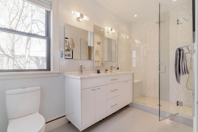 bathroom with double vanity, a sink, a shower stall, toilet, and baseboard heating