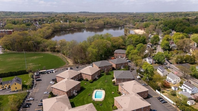 aerial view of property and surrounding area featuring a nearby body of water, a heavily wooded area, and nearby suburban area