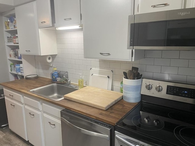 kitchen with white cabinetry, wooden counters, a sink, and stainless steel appliances