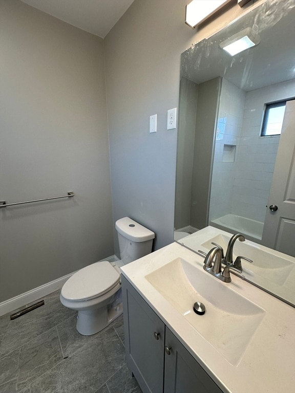 bathroom featuring tiled shower, vanity, and toilet