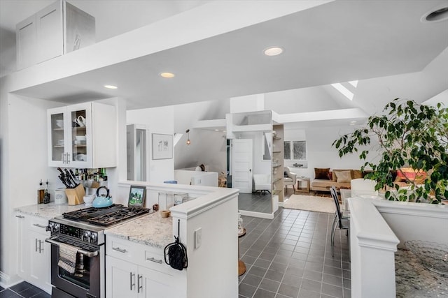 kitchen featuring light stone countertops, white cabinetry, dark tile patterned floors, and high end stainless steel range