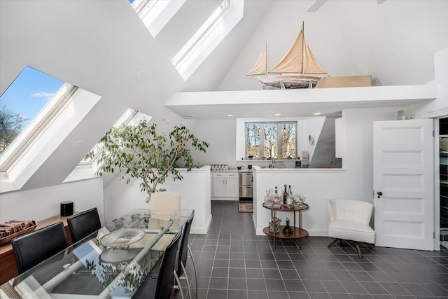 dining area with a skylight, a towering ceiling, and dark tile patterned flooring