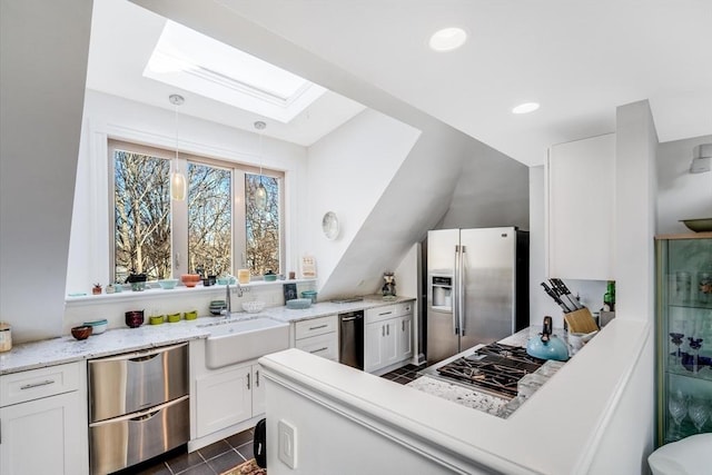 kitchen with stainless steel appliances, sink, dark tile patterned flooring, white cabinets, and hanging light fixtures