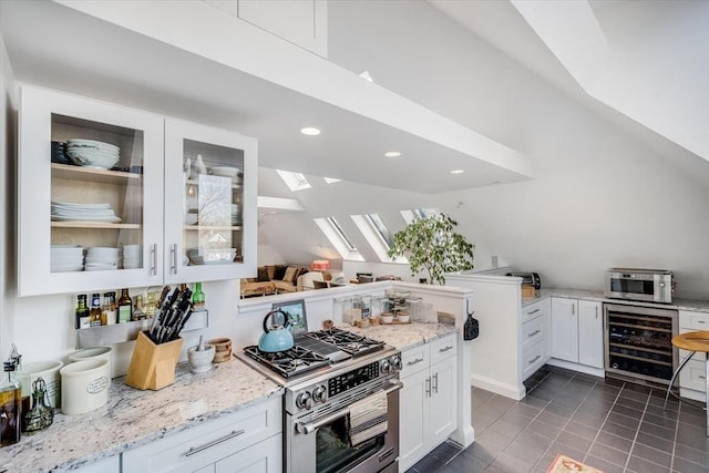 kitchen featuring white cabinets, wine cooler, a skylight, light stone counters, and stainless steel appliances