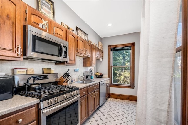 kitchen featuring tasteful backsplash, sink, light tile patterned floors, and appliances with stainless steel finishes