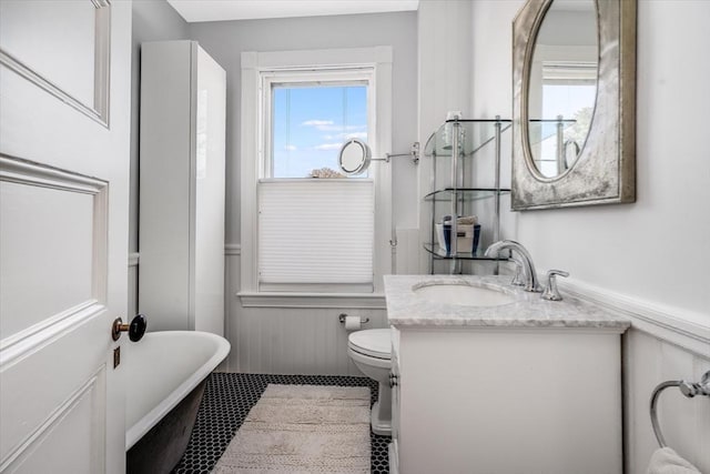 bathroom featuring a washtub, vanity, and toilet