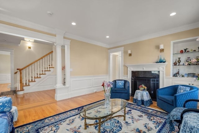 living room featuring ornamental molding, built in features, a fireplace, and hardwood / wood-style flooring