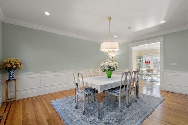 dining room with ornamental molding and light hardwood / wood-style flooring