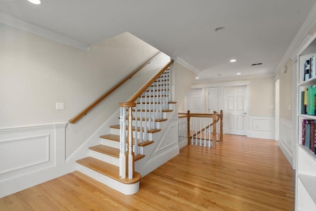 stairway with ornamental molding and wood-type flooring