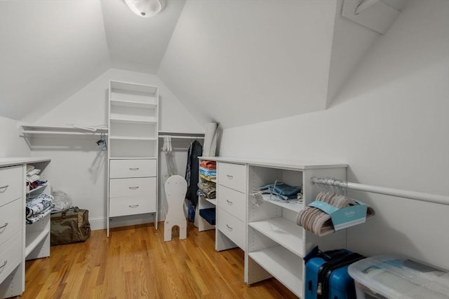 walk in closet with vaulted ceiling and light hardwood / wood-style floors