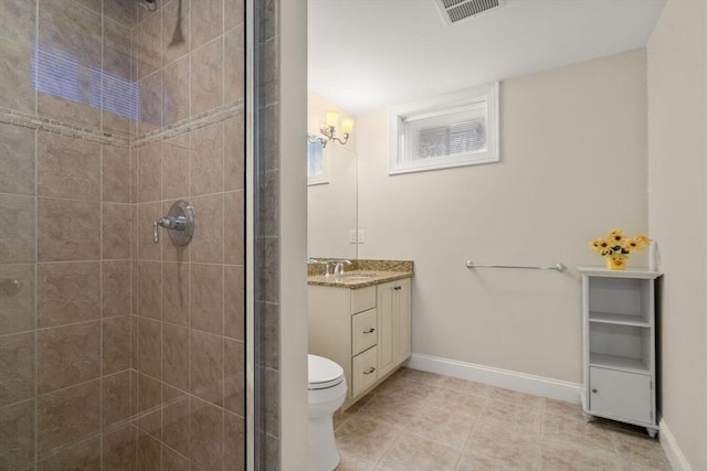 bathroom featuring tile patterned floors, a tile shower, vanity, and toilet