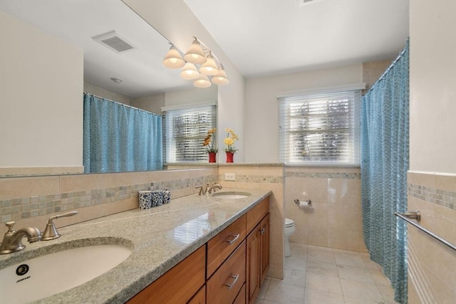 bathroom featuring toilet, tile patterned flooring, tile walls, and vanity