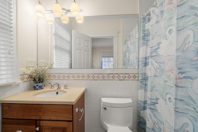 bathroom with tile walls, toilet, a shower with shower curtain, and vanity