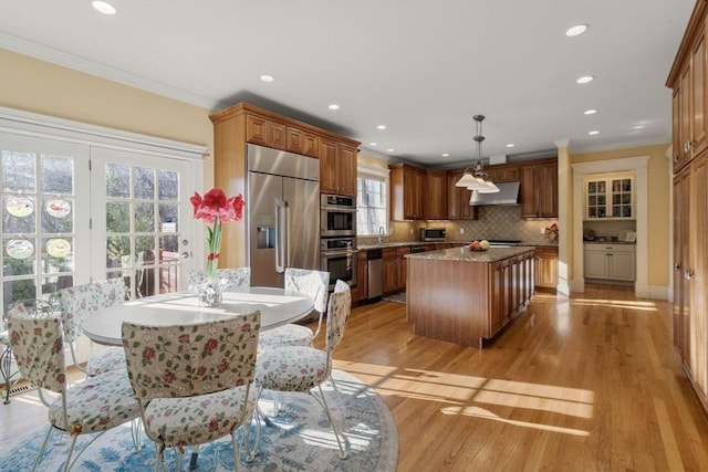 kitchen featuring a center island, hanging light fixtures, stainless steel appliances, decorative backsplash, and crown molding