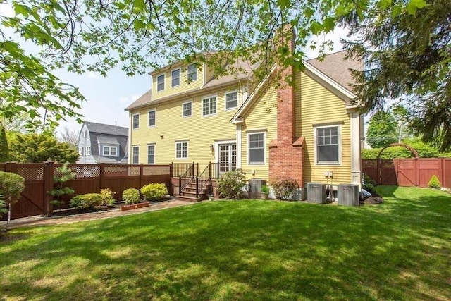 rear view of property with cooling unit and a lawn